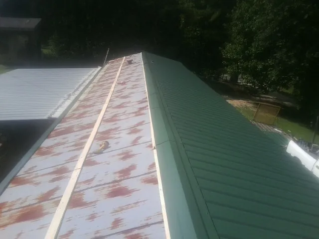 Old rusted panels beside newly installed green metal roofing — Wind Damage Roof Repair by Roofing Brothers in East Alton