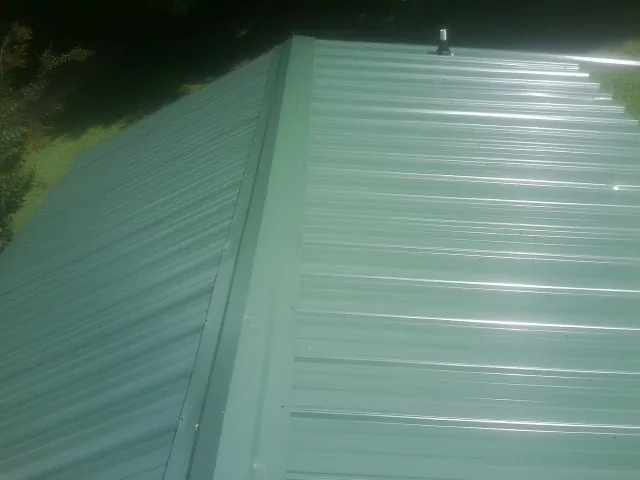 New green metal panels meeting at the ridge of a roof — Flat Roof Repair work by our crew in East Alton