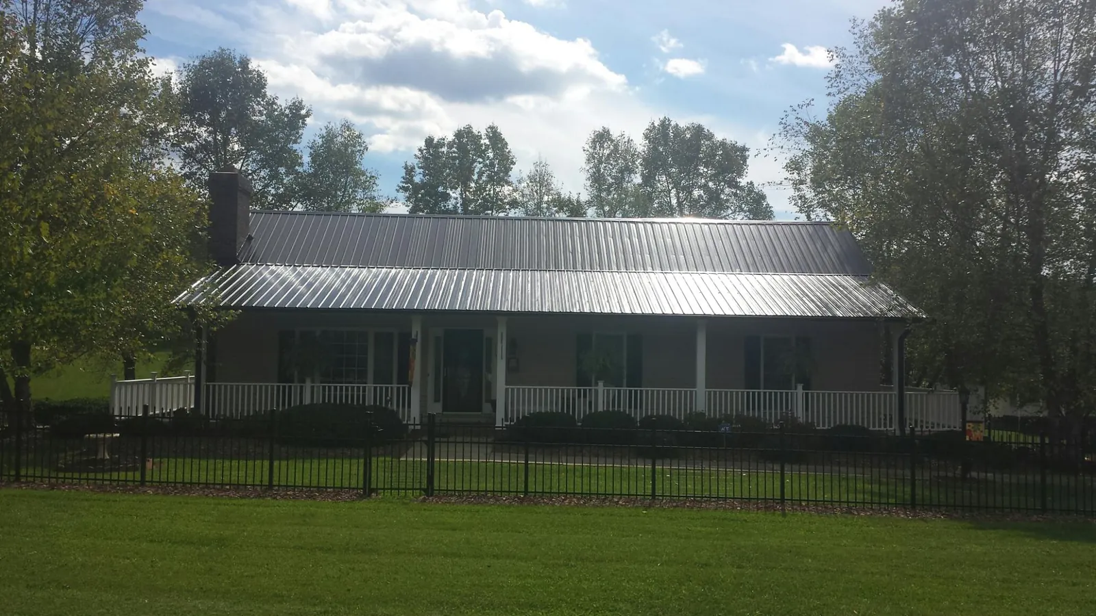 Gray metal roof on a brick ranch with a full width front porch — Gutter Guard Installation work by our crew in East Alton