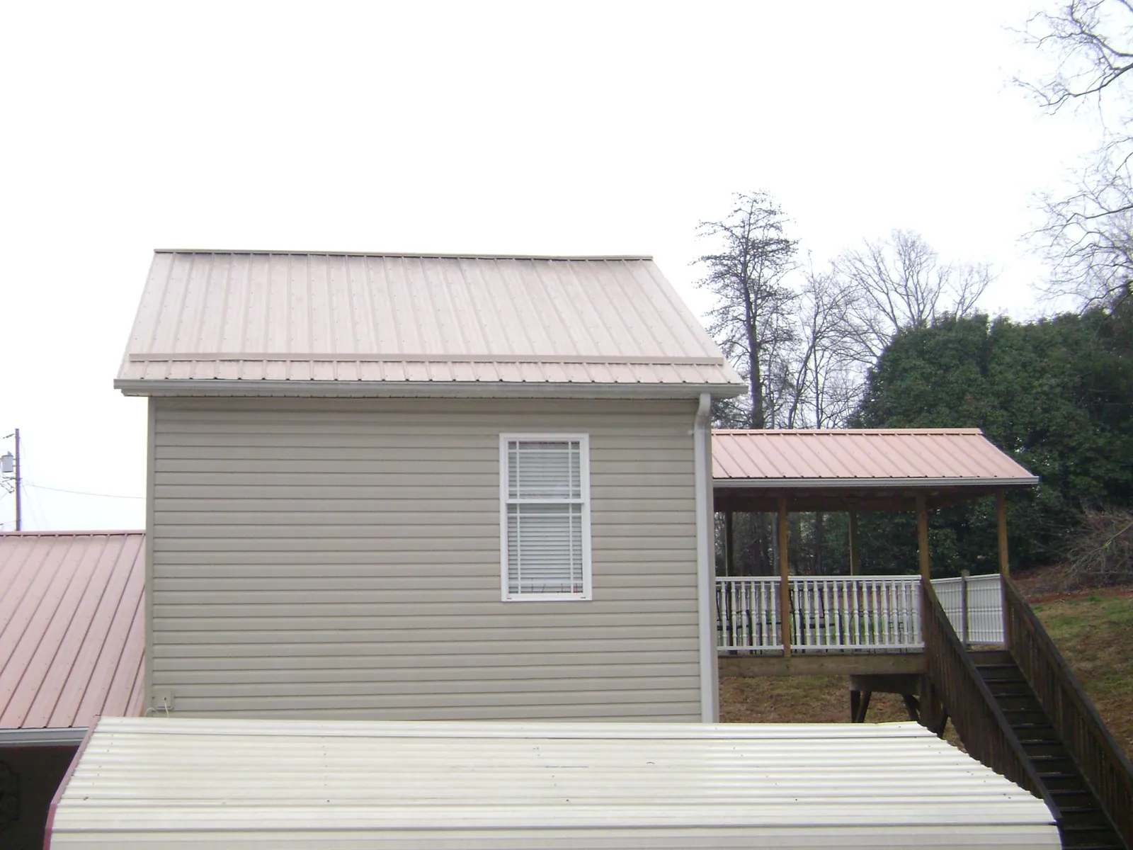 Tan metal roofs on a two story addition and attached porch, from a Roof Replacement job in East Alton