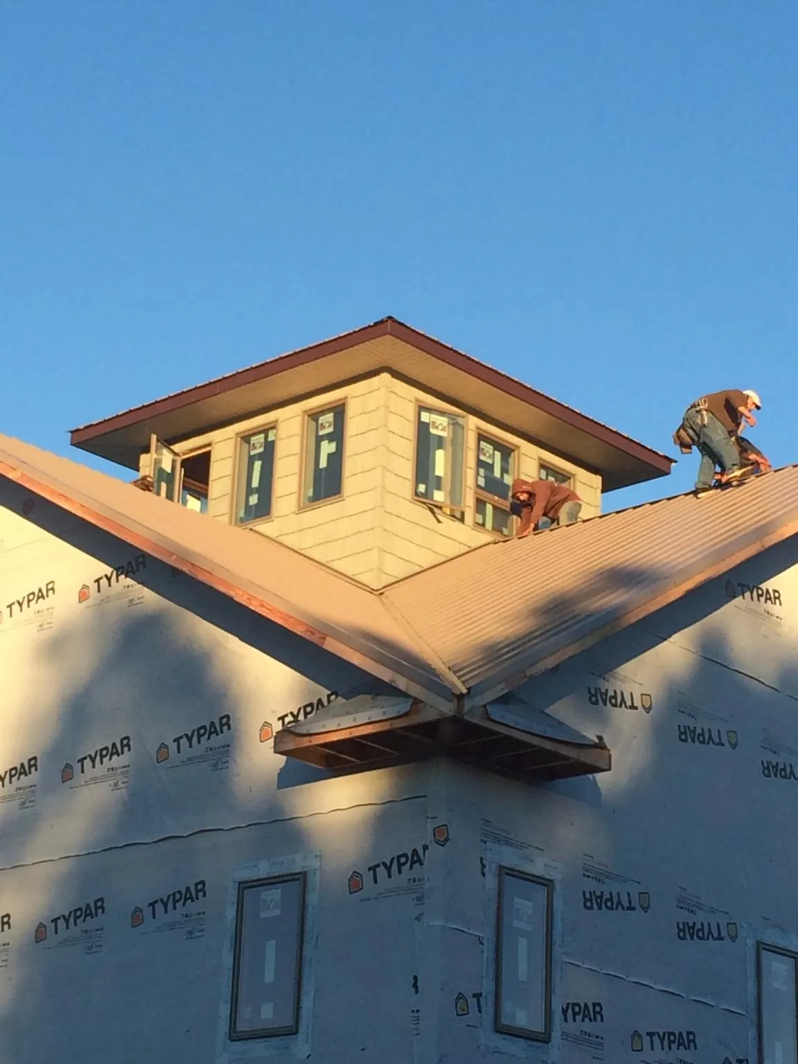Roofers working around a rooftop cupola on a new metal roof at sunset — Roof Waterproofing in East Alton by Roofing Brothers